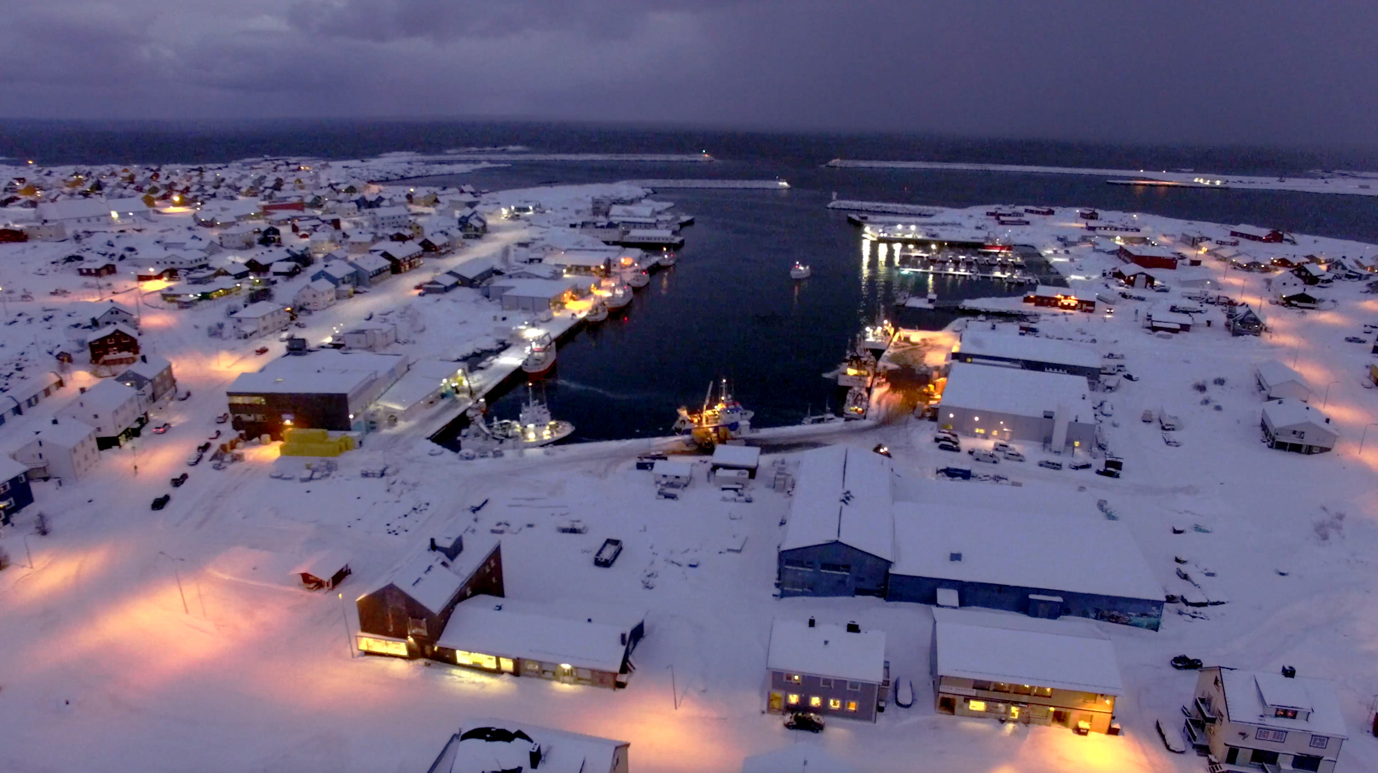 Flatt område med sittegruppe, og diverse. I bakgrunnen ser man en firkantet fabrikk med Lerøy-logo. Det er fint vær og nesten skyfri himmel